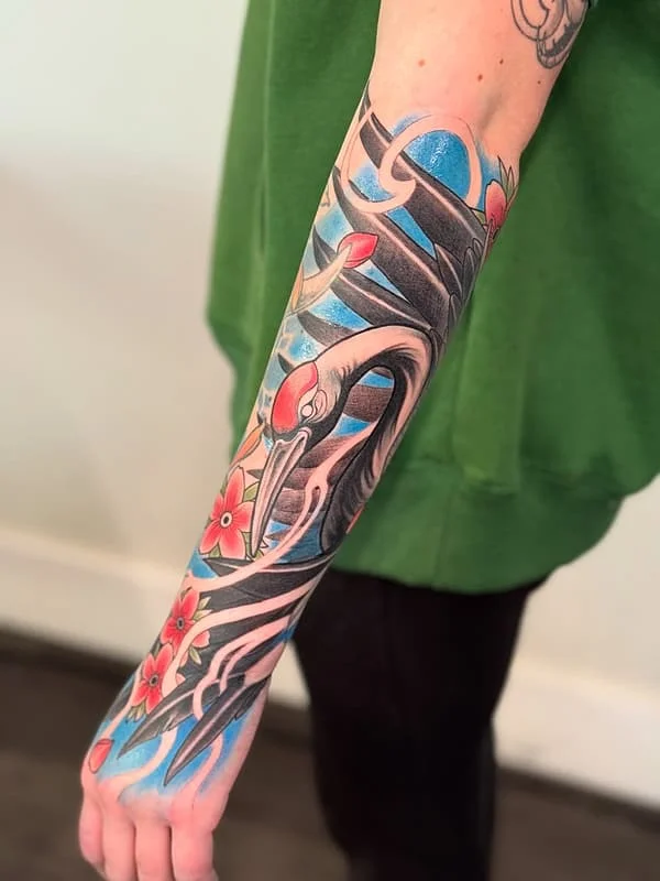 Japanese crane tattoo with flowers on forearm.