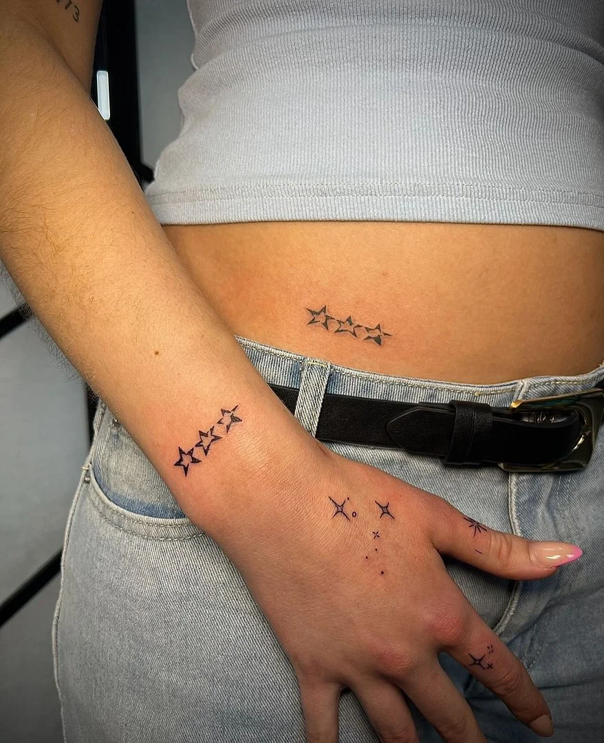 Minimalist star tattoos on wrist and hip.