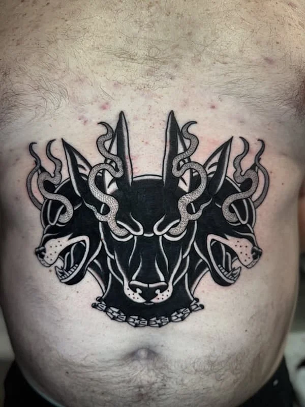 Three-headed dog tattoo with snakes on chest.