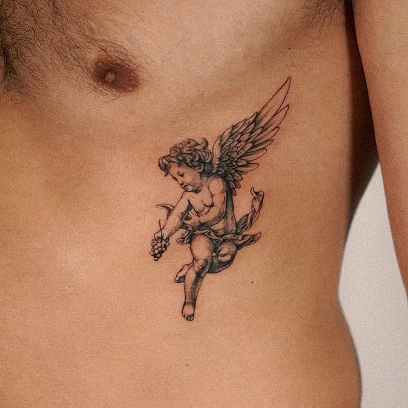 Medium black-and-grey cherub tattoo on rib.