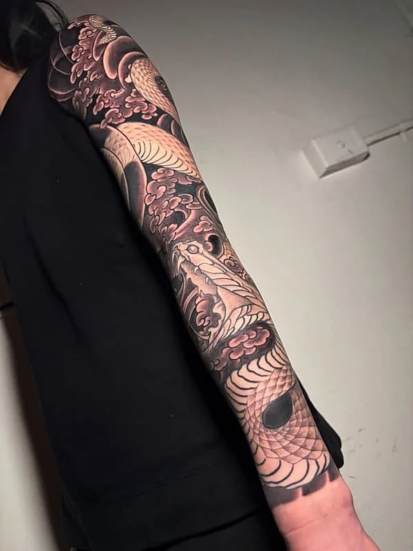 Black and grey illustrative half sleeve of koi fish and waves