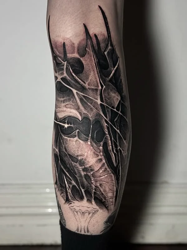 Large black-and-grey skull tattoo on leg.