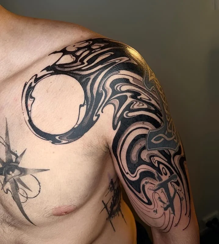 Abstract blackwork tattoo on shoulder and arm.