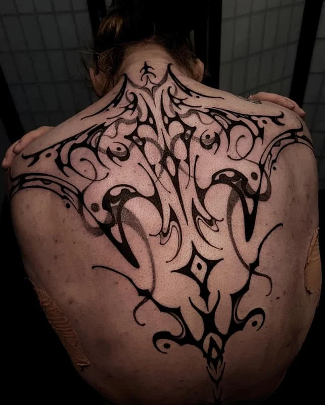 Large blackwork tribal tattoo on a person's back.
