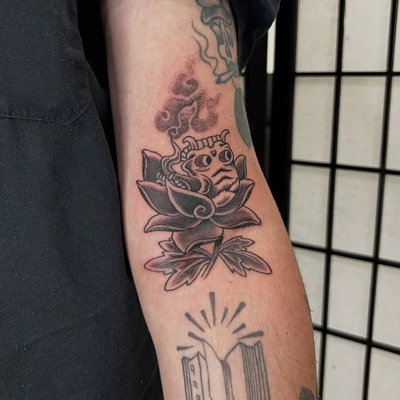 Japanese-style tattoo of a frog and lotus flower on arm.