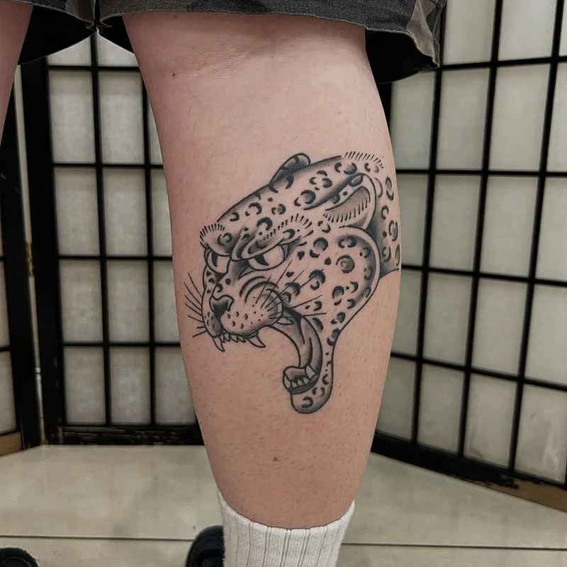 Black-and-grey leopard tattoo on calf.