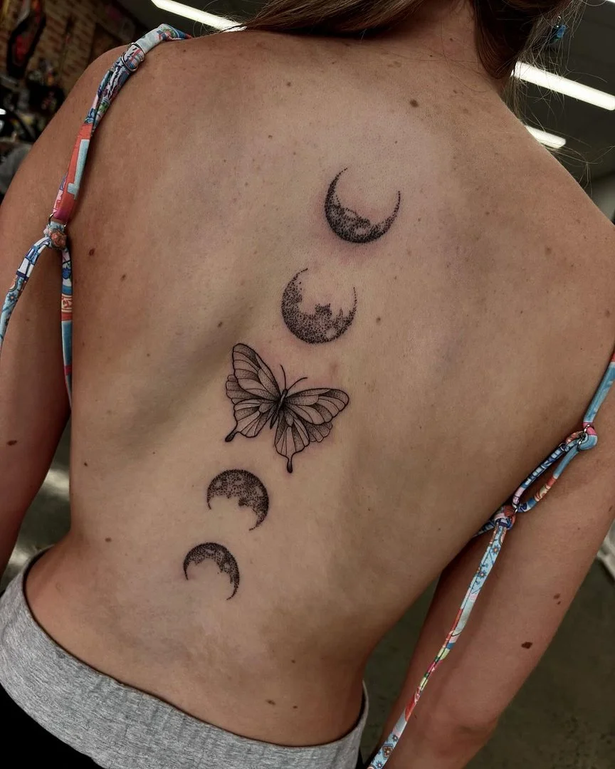 Butterfly and crescent moons tattoo on a woman's back.