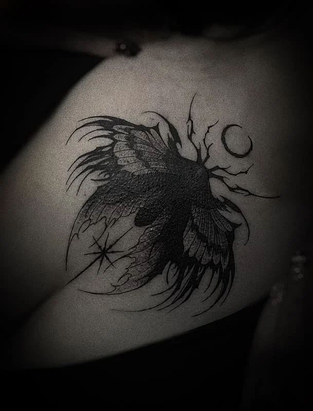 Blackwork butterfly tattoo on shoulder with moon and stars.