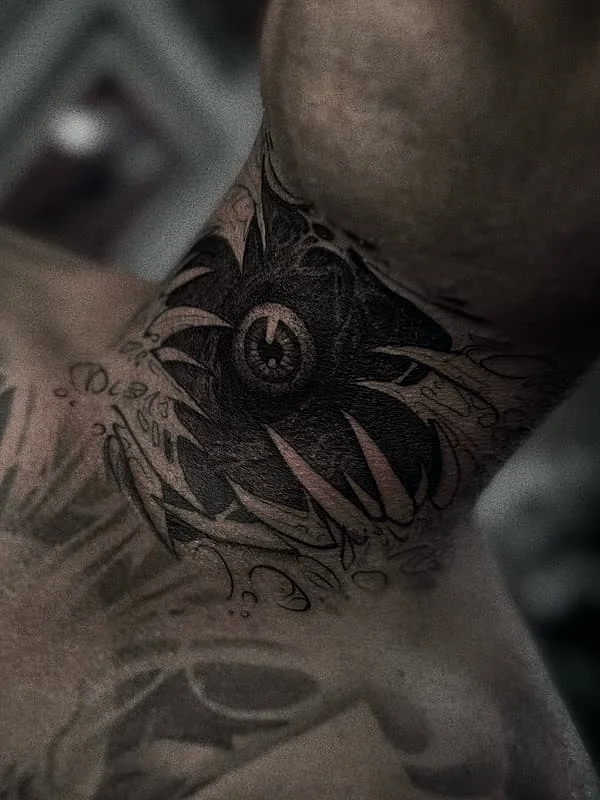 Intricate black and grey eye tattoo on neck.
