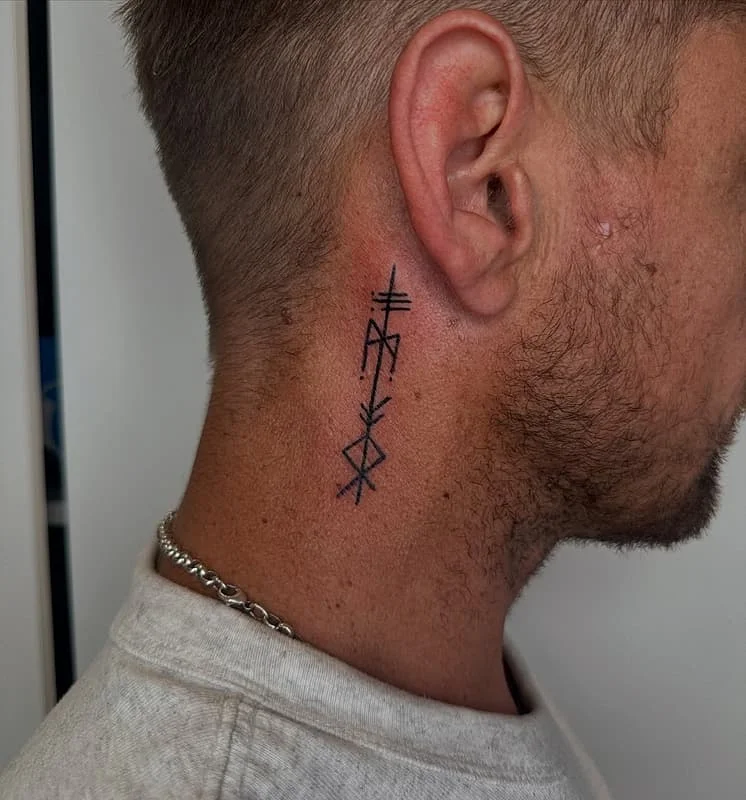 Minimalist blackwork tattoo behind the ear.