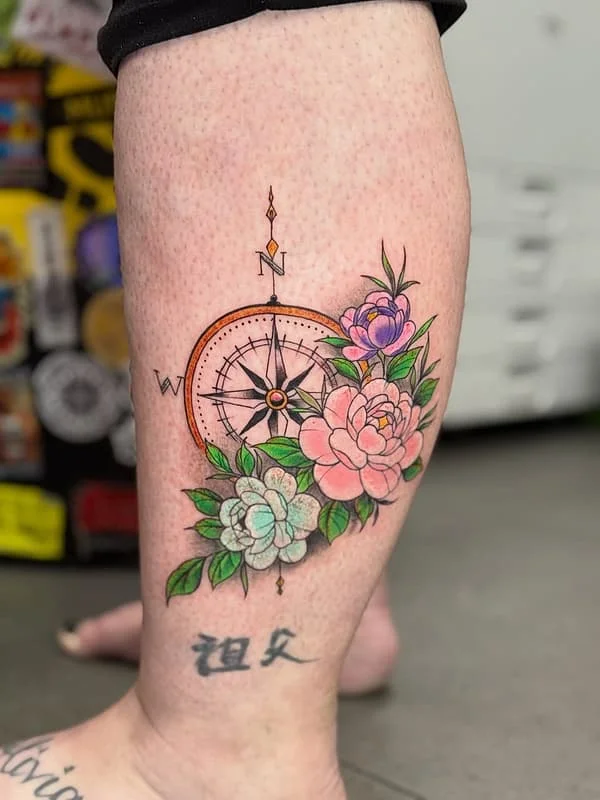 Colorful compass tattoo with flowers on calf.