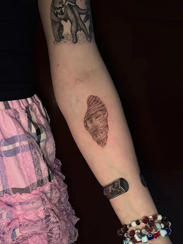 Blackwork shell tattoo on forearm.