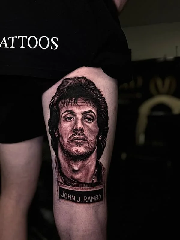 Realistic portrait tattoo of John J. Rambo on thigh.