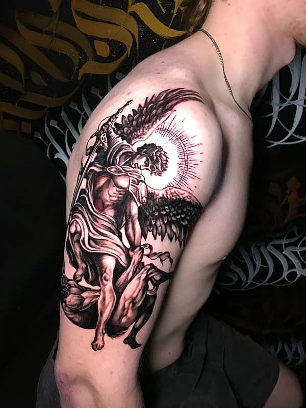 Detailed black-and-grey angel tattoo on shoulder and arm.