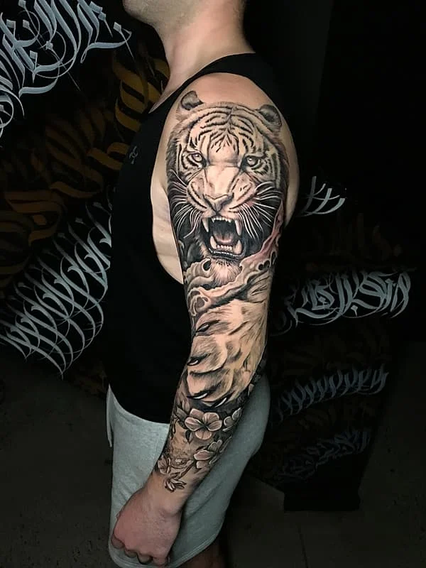Realistic full-sleeve tattoo of a roaring tiger.
