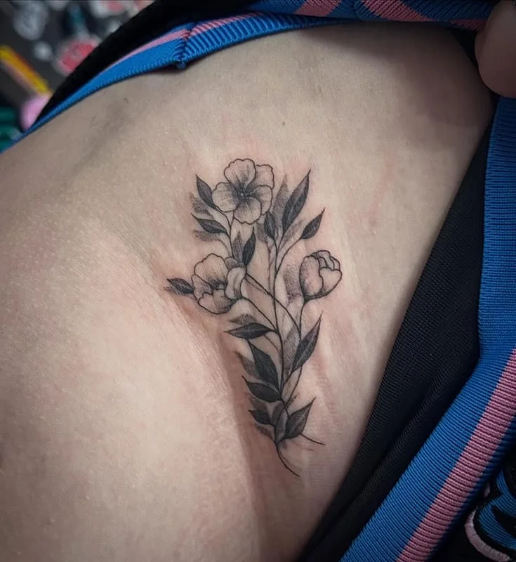 Medium black-and-grey floral tattoo on rib.