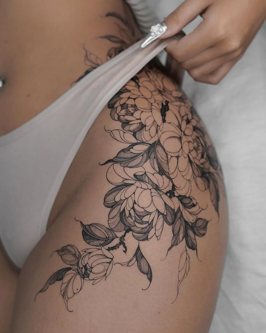 Intricate blackwork floral tattoo on a thigh.