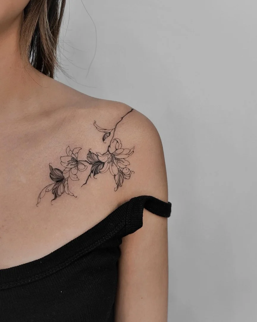 Delicate floral tattoo on a woman's shoulder.
