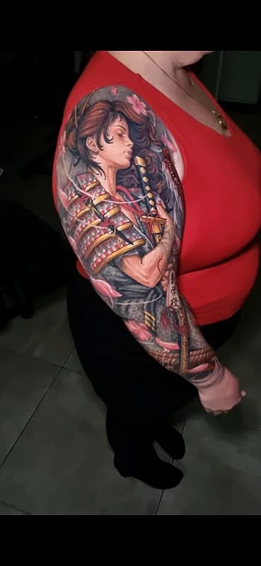 Full-sleeve tattoo of a samurai warrior with flowers.