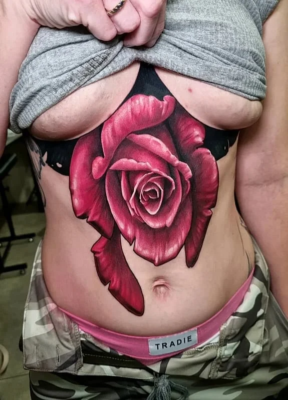 Large realistic rose tattoo on chest and rib.