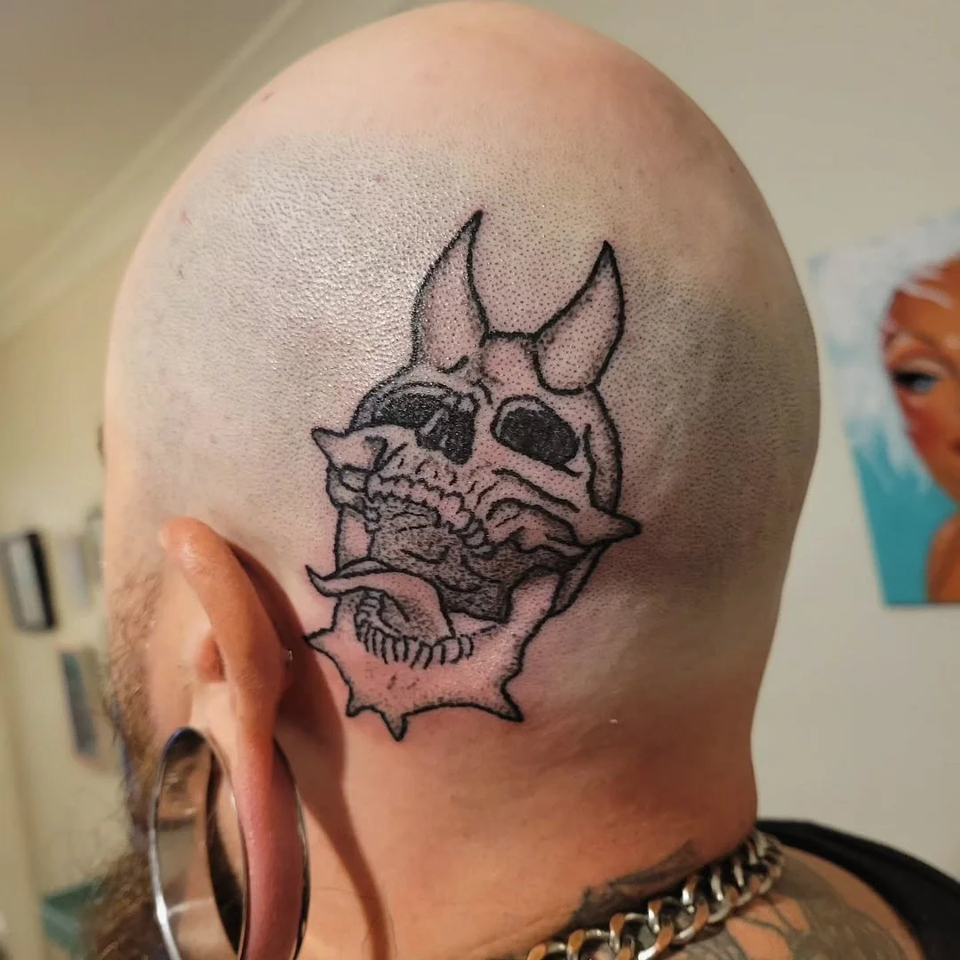 Illustrative skull tattoo with devil horns on the back of the head.