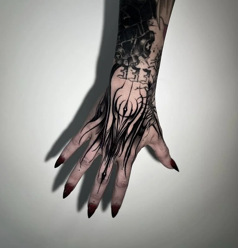 Intricate blackwork tattoo on hand and forearm.