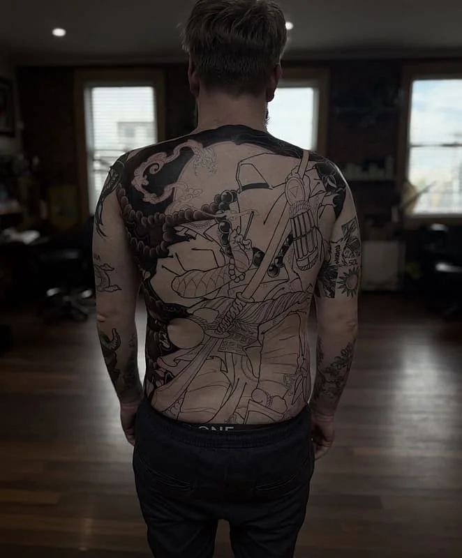 Large illustrative back tattoo of a warrior in battle.