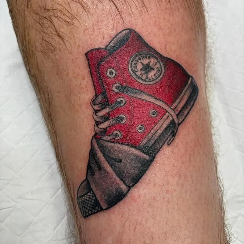 Realistic red Converse shoe tattoo on calf.