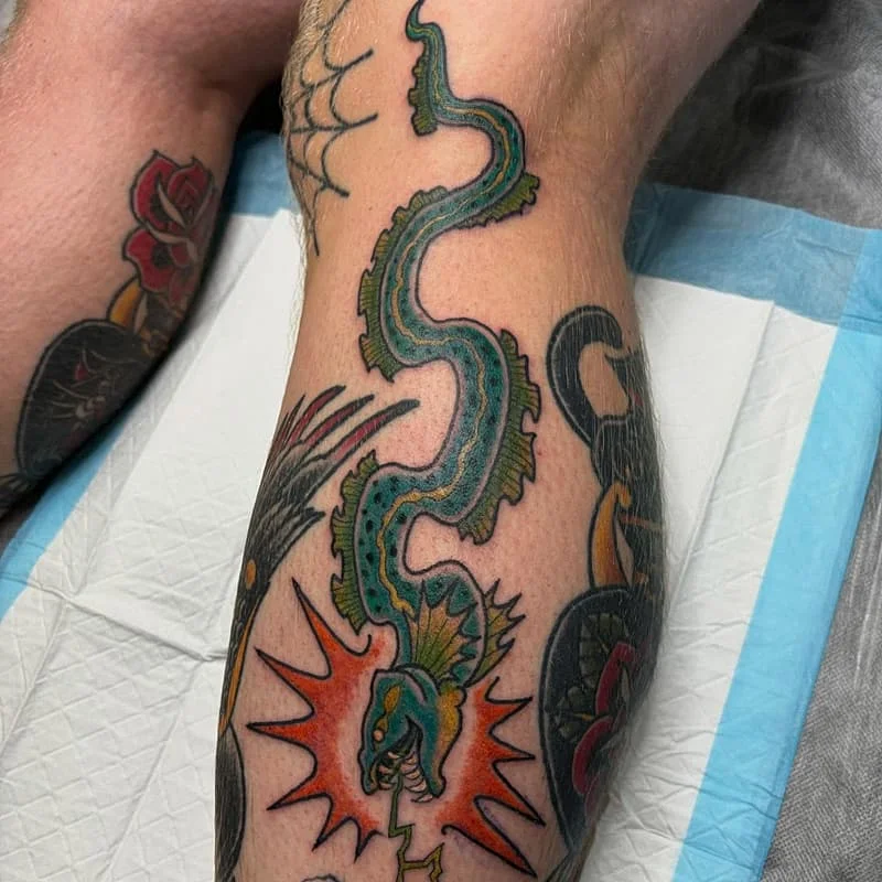 Colorful dragon tattoo on calf with lightning.