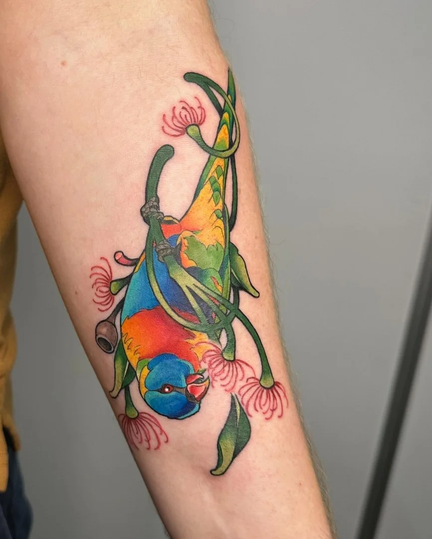 Colorful bird tattoo on forearm with flowers.