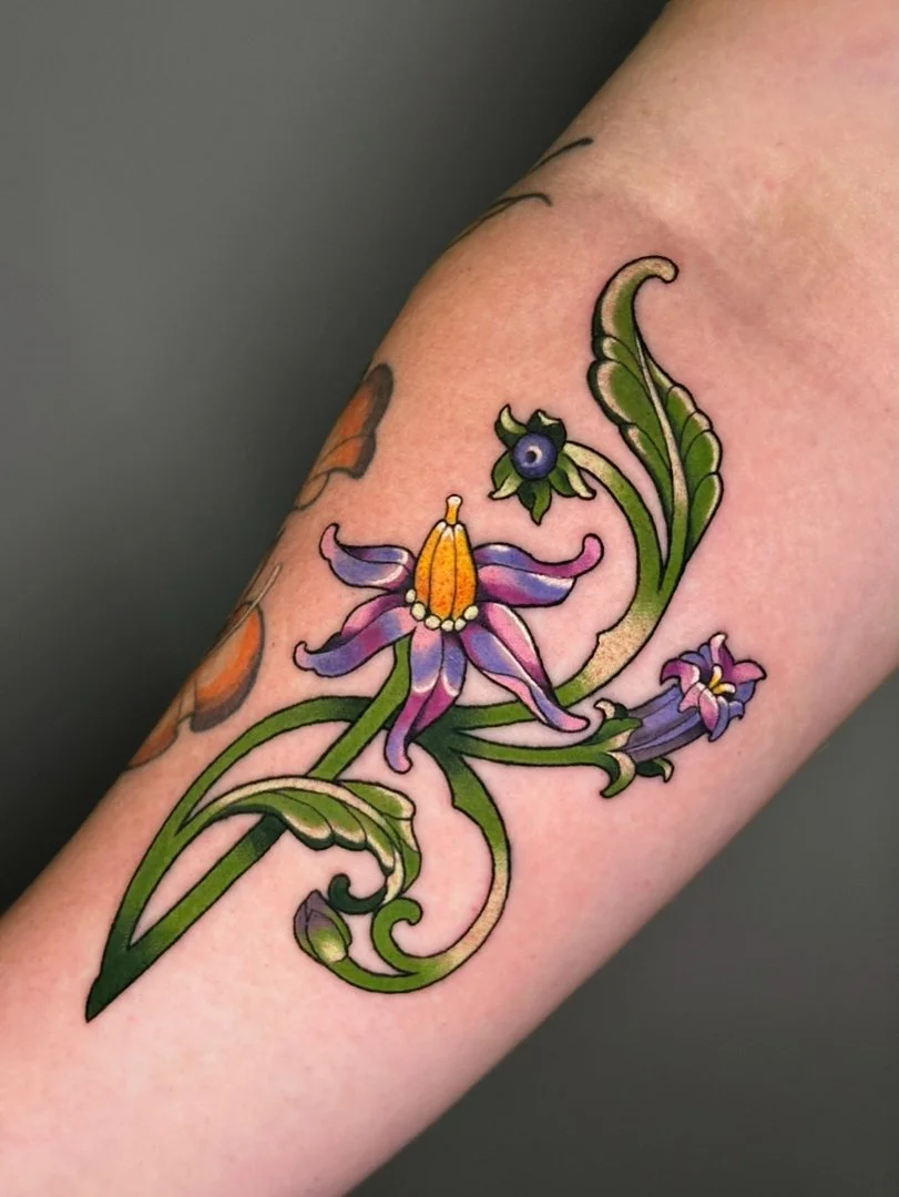 Vibrant watercolor floral tattoo on forearm.
